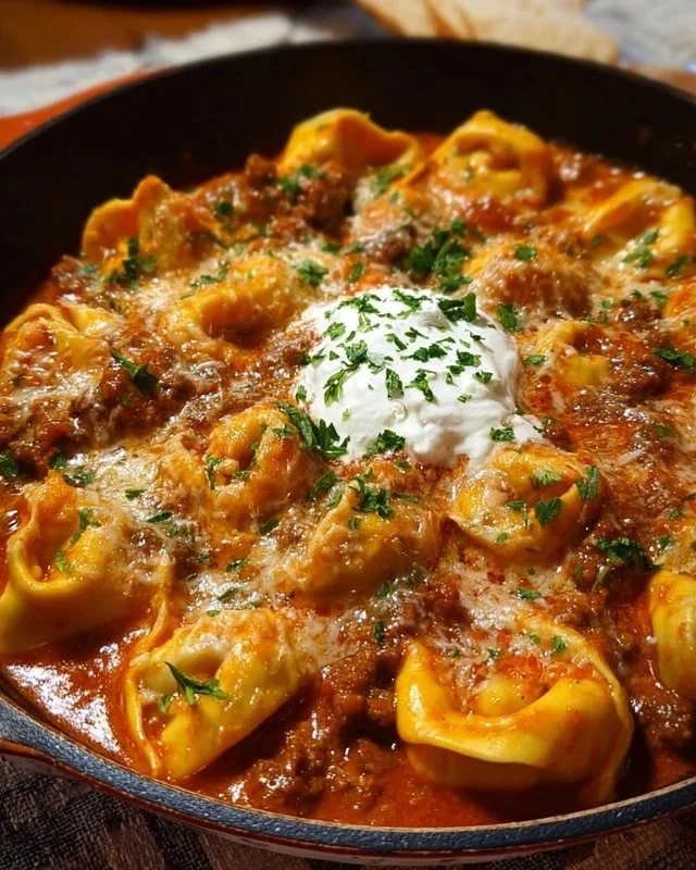 Cheesy beef enchilada tortellini served in a bowl, topped with cheese and garnished.