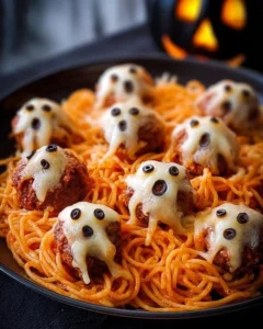 Plate of spooky spaghetti with cheesy monster meatballs for Halloween dinner