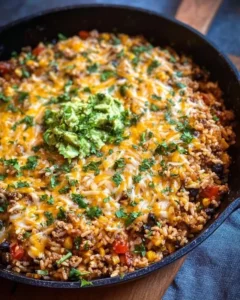 Cheesy Taco Rice Skillet topped with cheese and spices in a skillet