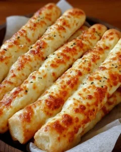 Homemade cheesy breadsticks with melted cheese and herbs on a baking tray.