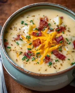 Bowl of loaded potato soup topped with cheese, bacon, and chives for a delicious meal.