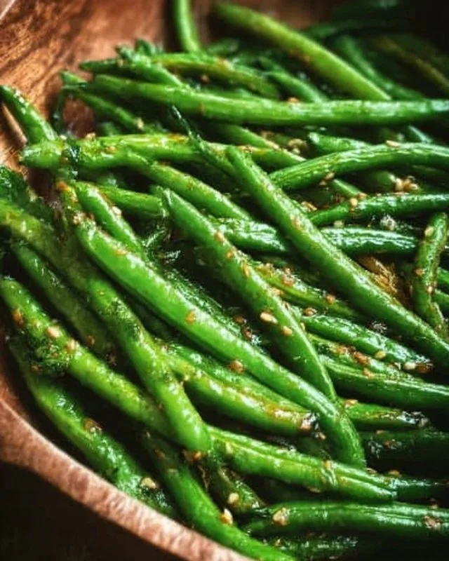 Plate of miso green beans garnished with sesame seeds and herbs