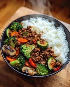Spicy ground beef stir-fry bowl with garlic vegetables and rice