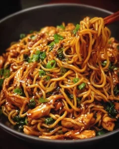 Sticky Garlic Chicken Noodles plated with fresh herbs and sesame seeds