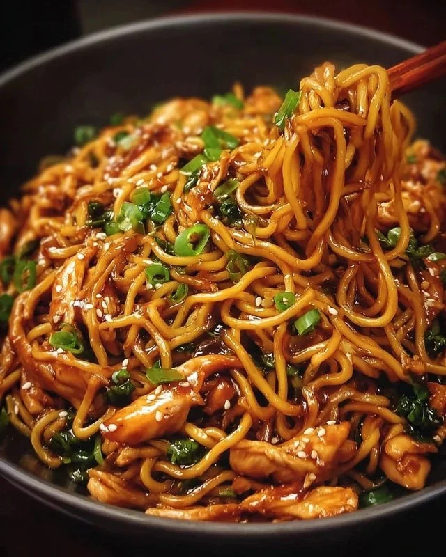 Sticky Garlic Chicken Noodles plated with fresh herbs and sesame seeds