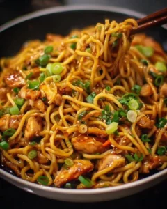 Delicious sticky garlic chicken noodles served in a bowl with fresh herbs.