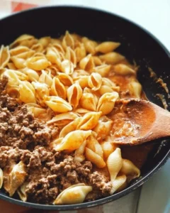 Creamy beef and shells dish topped with herbs in a white bowl