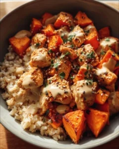 Healthy chicken and sweet potato rice bowl garnished with fresh vegetables