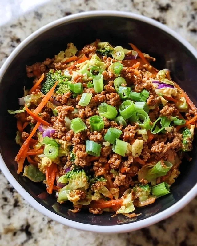 High protein egg roll in a bowl topped with fresh vegetables and savory sauce.