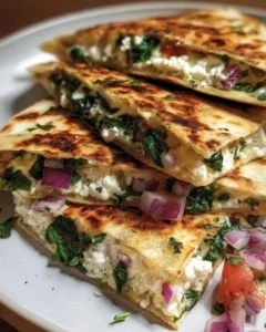 Mediterranean Quesadillas with spinach, feta, mozzarella, and red onion served on a plate