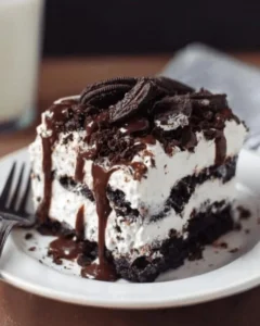 Delicious Oreo Poke Cake topped with cream and crushed Oreos