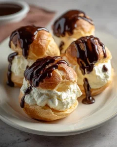 Delicious profiteroles filled with cream and topped with chocolate sauce