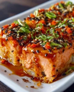 Delicious spicy salmon sushi bake served in a dish, showcasing layers and toppings.