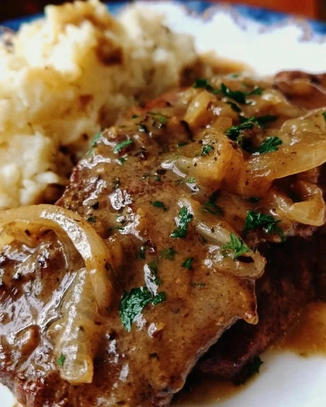 Delicious beef liver with onions smothered in rich gravy served on a plate.