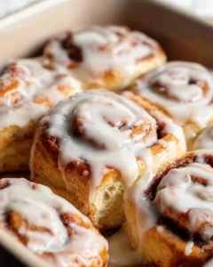 Delicious homemade cinnamon rolls with icing on a baking tray