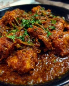 Plate of Chicken Bhuna Masala garnished with fresh herbs.