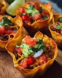 Plate of crispy taco cups filled with meat, cheese, and toppings.