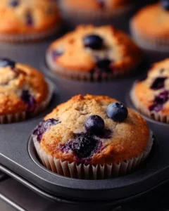Hearty blueberry protein muffins on a wooden table with fresh blueberries