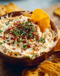 Bowl of high protein crack dip topped with herbs and served with veggies.