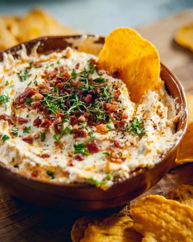 Bowl of high protein crack dip topped with herbs and served with veggies.