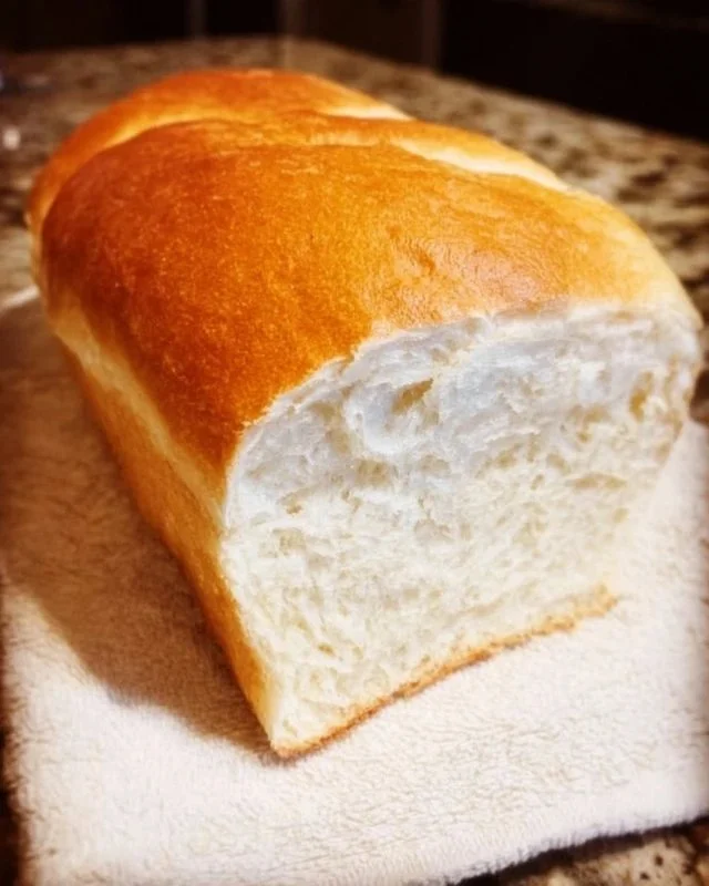 Loaf of homemade Amish white bread on a wooden table.