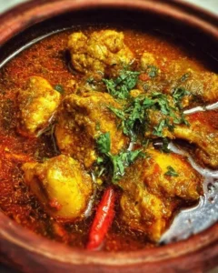 Bowl of Indian Chicken Curry with rice and garnish on a wooden table