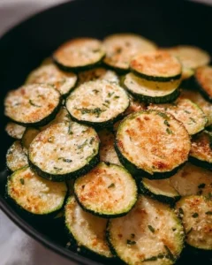 Bowl of crispy oven-baked zucchini chips garnished with herbs