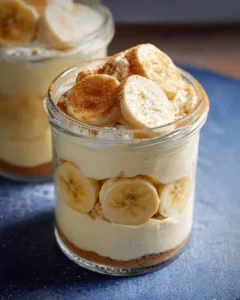 Protein banana pudding in a bowl topped with sliced bananas