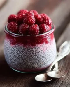 Raspberry chia pudding with maple syrup in a glass bowl garnished with fresh raspberries