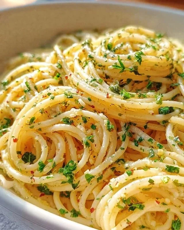 Plate of spaghetti with garlic and oil topped with parsley and chili flakes